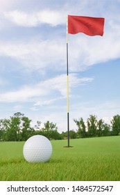 Red flag on golf course putting green with a ball near the hole