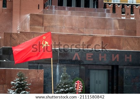 The red flag of the Soviet Union with a hammer and sickle on the background of the Lenin Mausoleum. Communism in Russia is a concept
