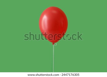 Red floating balloon on green background