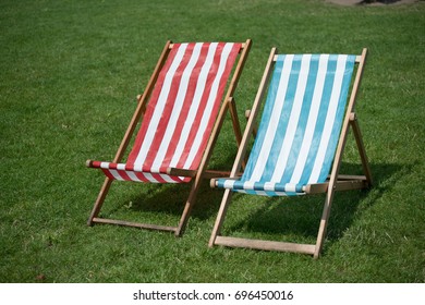 Red And Foldable Portable Green Deck Chairs With Grass In The Background