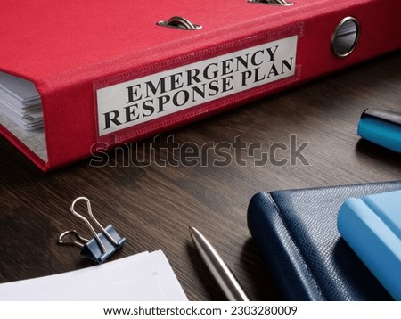 Red folder with Emergency response plan on the desk.