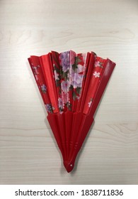 The Red Folding Hand Fan On The Wooden Desk