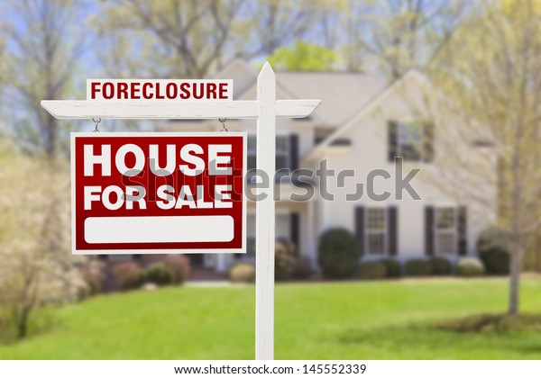 Red Foreclosure Home For Sale Real Estate Sign in\
Front of House.
