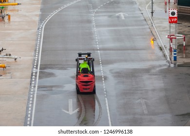 Red forklift rides on the road at the airport in the rain, autoloader