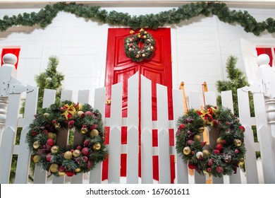 Red Front Door Of The White House Nicely Decorated For Christmas With Fir Trees, A Wreath And With Sparkling Lights.