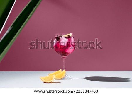 Red fruit cocktail with orange pieces on a maroon background