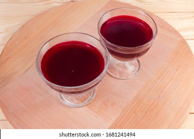 Red fruit gelatin dessert in two glass ice cream cups on the wooden surface
