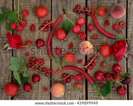 red fruits, vegetables and flowers on wooden background - currants, raspberries, strawberries, strawberry, peach, pepper, chilli, tomato, rose, cherry,