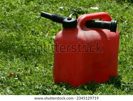 Red fuel canister with dispenser on the grass
