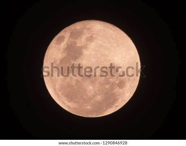 Red full moon on dark night sky. The full moon is\
lunar phase when It appear fully illuminated from Earth\'s\
perspective. It occurs when Earth is located between Sun and Moon\
appears as a circular disk