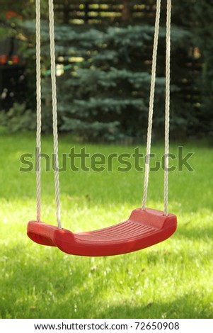 Red garden swing hanging in garden