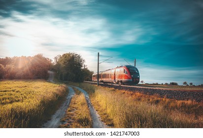 Red German Train Traveling On Railway Tracks Through Nature, Near A Rural Alley, At Sunset, Near Schwabisch Hall, Germany. Travel Concept.