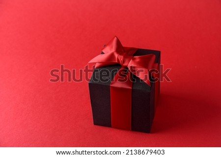 Red gift box with red bow on red background