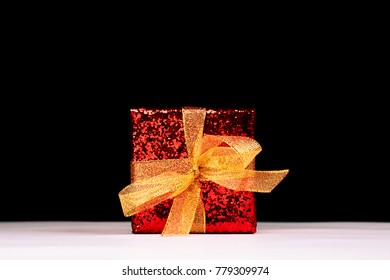 Red Gift Box With Golden Ribbon Over Black Backdrop. Front View.