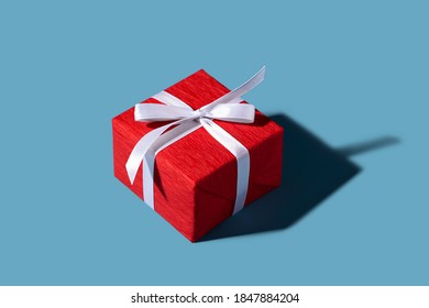 Red Gift Box With White Ribbon And Bow On The Blue Background. Christmas And New Year Concept. Greeting And Celebration. Isolated. Isometric.