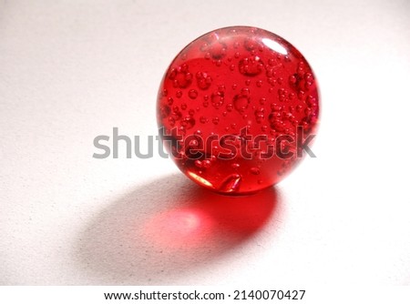 red glass marble with bubbles, ball, marble on a white background