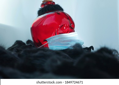 A Red Glass Mock-up Of A Skeleton's Skull With Protective Mask Surrounded By A Black Mink. The Concept Of Genetic Changes Of Coronavirus On Farms Breeding Mink, Cull Millions Of Mink