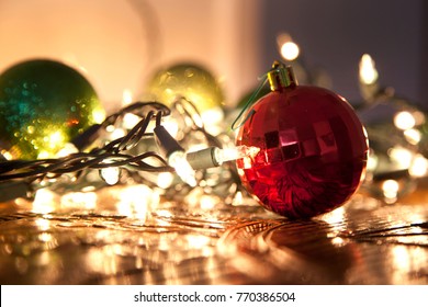  a red glass ornament ball with christmas lights tangled in the background