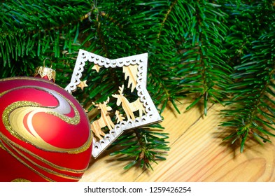 Red and Gold Christmas balls with decor and green fir branch on wood background. Xmas background.