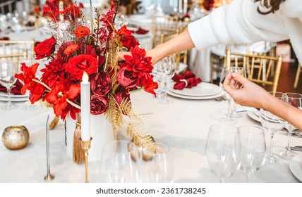 Red gold color flower decor for Chinese New Year celebration. Girl woman florist, decorator, organizer of events, parties, wedding planner making floral arrangement, festive bouquet, table decoration.
