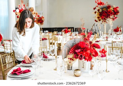 Red gold color flower decor for Chinese New Year celebration. Girl woman florist, decorator, organizer of events, parties, wedding planner making floral arrangement, festive bouquet, table decoration.