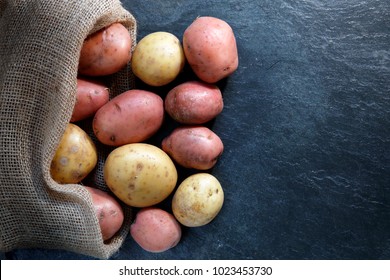 Red And Gold Potatoes In Hessian Sack On Slate Table Top With Copy Space