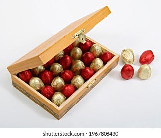 Red And Golden Egg Shaped Easter Chocolates In Wooden Gift Box. Easter Chocolate Eggs Wrapped With Aluminum Foil, Easter Gift For Kids In Wooden Basket. Special Days Celebration Gourmet Gift.