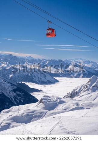 Red gondola of cable car seen from Bellecote glacier, La Plagne ski resort, France,  in winter. Inversion clouds in valley