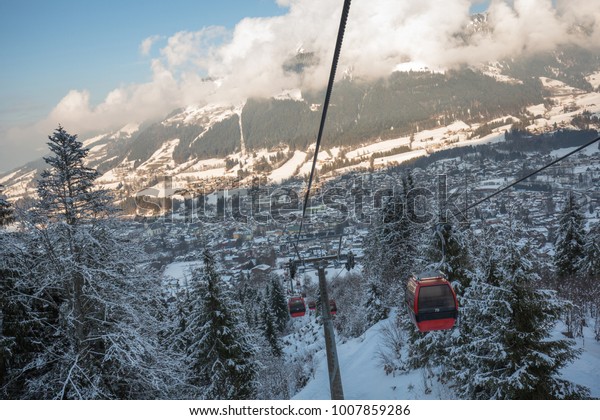 Red\
gondola car lift on the ski resort over forest\
trees