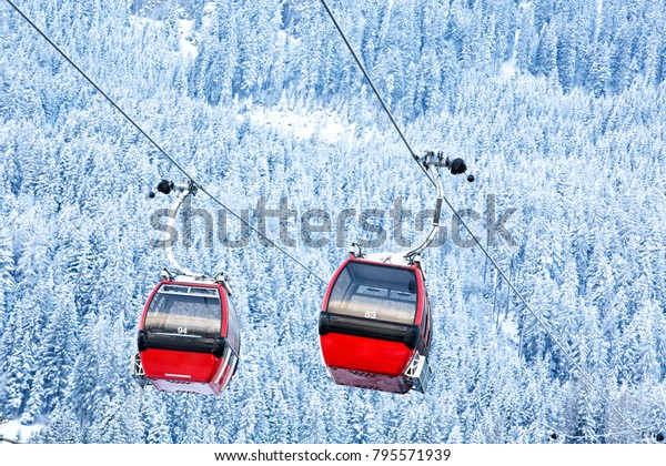 Red\
gondola car lift on the ski resort over forest trees\
