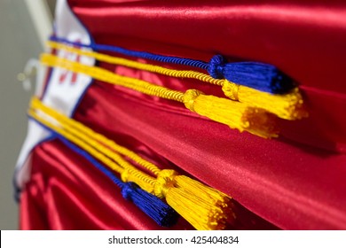 Red Graduation Gown With Gold Cords And White Stole