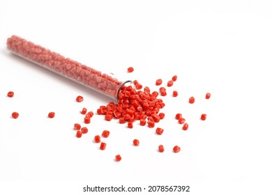 Red granules of polypropylene, polyamide in a measuring beaker and a test tube on a white background. Chemical products. Plastic, polymers and microplastics.