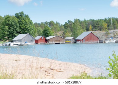 Red and gray boathouses, rock and trees in the archipelago in Aland, Finland