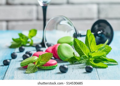 Red and green french cookies macaroons with a martini glass on a blue background. - Powered by Shutterstock