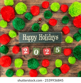 Red and green pompoms with wooden blocks and text happy holidays and 2025 on wood - Powered by Shutterstock