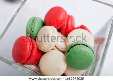 Red, green, and white macarons in glass bowl, close-up photo. Traditional Christmas cookies.
