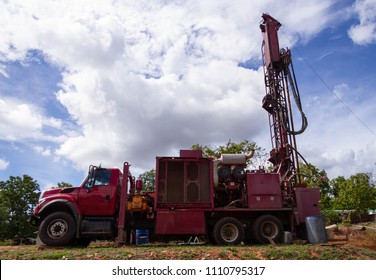 The Red Groundwater Well Drilling machine in suburban yard.