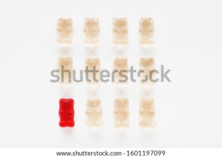 Red gummy bear standing out of the crowd with its distinctive color. Diversity and difference