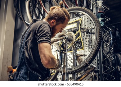 Red hair bearded mechanic removing bicycle rear cassette in a workshop. - Powered by Shutterstock