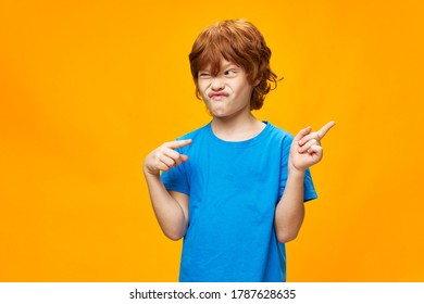 Red hair blue T-shirt yellow background boy shows the direction  - Shutterstock ID 1787628635