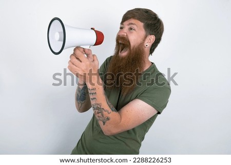 Red haired man wearing printed shirt over white studio background Through Megaphone with Available Copy Space