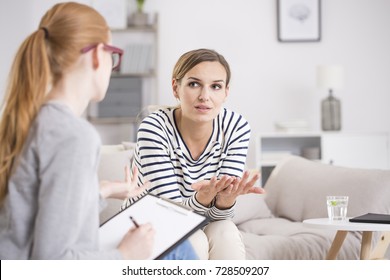 Red Haired Psychiatrist Listening To Her Patient Who Experienced Traumatic Events, Sitting On Beige Settee