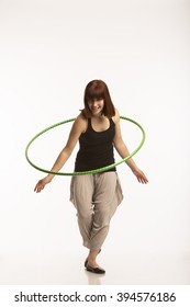 Red Haired Smiley Young Woman Playing With Hula Hoop In White Studio Background.