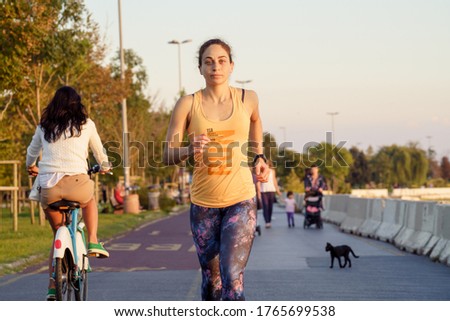 
Red haired woman jogging while running at sunset. Woman doing running at the seaside at sunset. The woman wears a yellow sports bodysuit that says run. healthy life concept.
