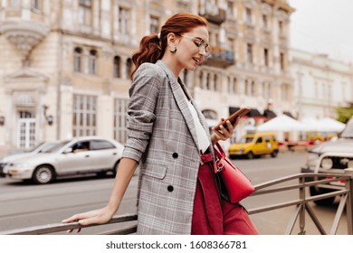 Red haired woman in stylish outfit chatting on phone