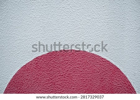 Red half circle shape painted on a rough white textured concrete wall background