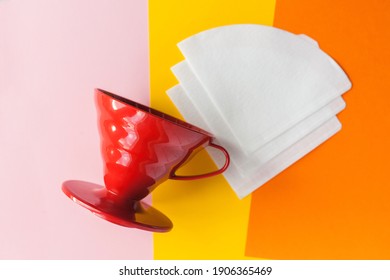 red hario or v60 and bleached paper coffee filters isolated on a colored background. Alternative brewing pour over coffee. Minimalistic abstract background. flat lay top view mock up - Shutterstock ID 1906365469