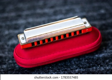 Red Harmonica Music Instrument On Top Of Its Case