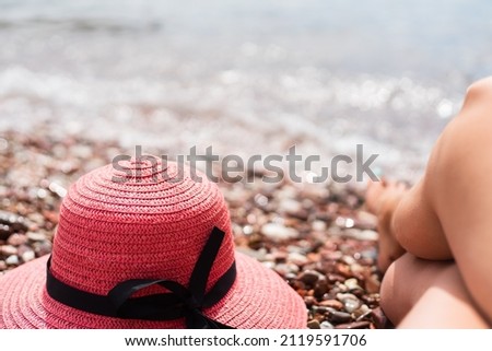 Red hat and woman's legs on the by the sea. Sunbathing. Rest on the sea. Relaxing on the beach. Selective focus.