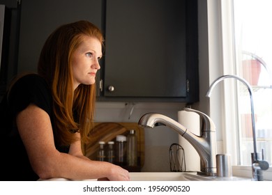 Red Head Caucasian Adult Mom Women Sad Depressed Hopeless Grief Anxiety Looking Out A Window From Kitchen